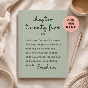 May include: Sage green journal with the text "chapter twenty five" and a heart symbol. The journal includes the text "Look how far you've come" and "Sophie" at the bottom. A pink sticker says "Add Her Name". A pen and a mug are also in the image.