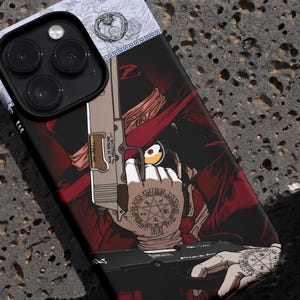 Puede incluir: Funda de teléfono negra con una ilustración detallada de un personaje sosteniendo un arma. La obra de arte es predominantemente roja y negra, con intrincados diseños de tatuajes en la mano del personaje. La funda tiene una parte superior blanca con un diseño.