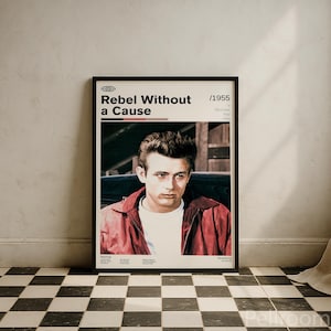Puede incluir: Póster enmarcado de la película "Rebelde sin causa" con James Dean. El póster, con marco negro, muestra el título de la película y el año 1955. Dean lleva una chaqueta roja y una camiseta blanca.