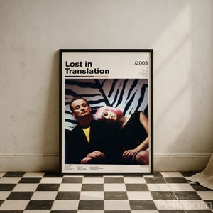 May include: A framed poster for the film "Lost in Translation" with a black frame. The poster features Bill Murray and Scarlett Johansson. The title and year are displayed on a cream background. The background behind the actors is a black and white zebra print.