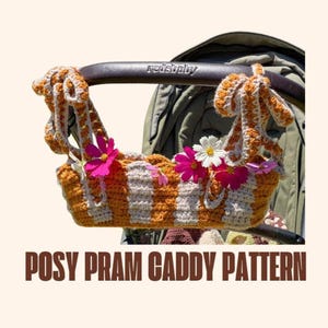 Könnte beinhalten: Gehäkelte Kinderwagen-Tasche in orange und cremefarbenen Streifen, verziert mit rosa und weißen Blumen. Die Tasche ist an einem Kinderwagen-Griff befestigt. Der Text "POSY PRAM CADDY PATTERN" ist unten zu sehen.