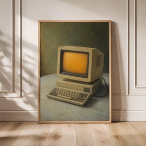 May include: A framed wall art print depicting a vintage beige desktop computer with a glowing orange screen. The computer consists of a bulky monitor sitting on a base unit with an attached keyboard, all rendered in a textured, painterly style.