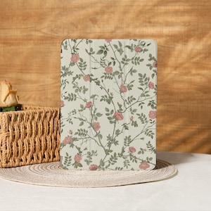 May include: A floral patterned tablet case featuring a cream background with pink roses and green leaves. The design is a repeating pattern of rose branches. The case is rectangular and appears to be made of a durable material.