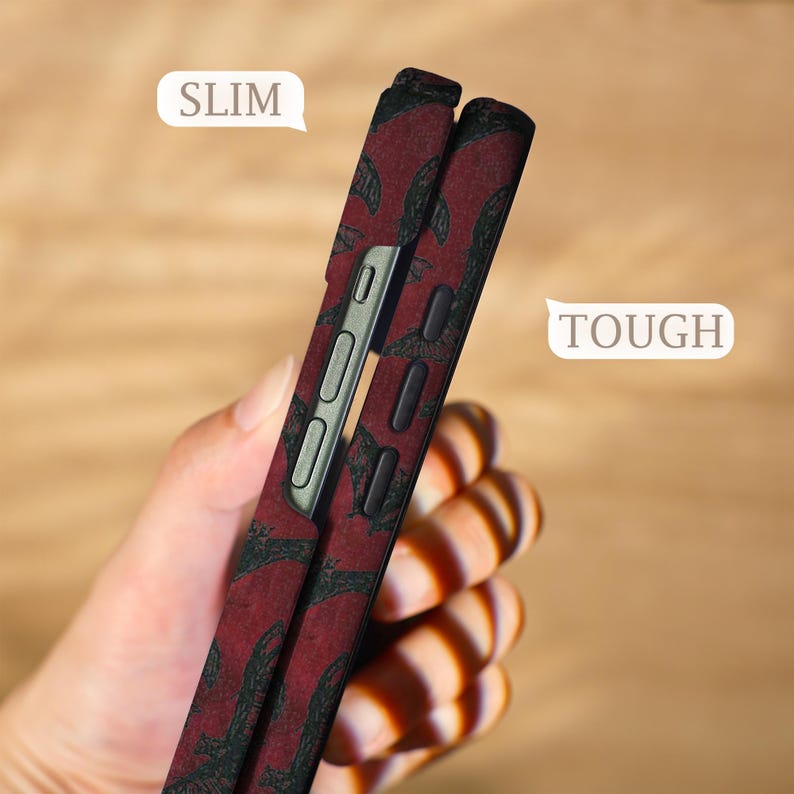 May include: A red and black patterned phone case with the words "SLIM" and "TOUGH" in white speech bubbles. The case has a slim profile and features a dark red background with a black design.