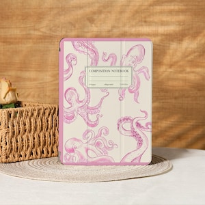 Peut inclure: Un cahier de composition rose et crème avec des illustrations de pieuvres roses. Le cahier a une bordure rose et le texte "COMPOSITION NOTEBOOK" dans une étiquette rectangulaire. Le cahier mesure 19,05 x 23,5 cm.