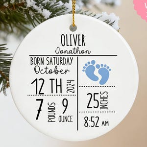 Pode incluir: Enfeite de cerâmica branca com fio dourado. Apresenta o nome "Oliver Jonathon", detalhes do nascimento, data, hora, peso (3,18 kg, 63,5 cm) e pegadas de bebê.