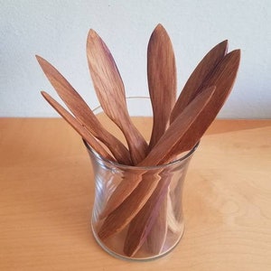 May include: A set of wooden cheese knives in a glass jar. The knives are all brown and have a natural wood finish.