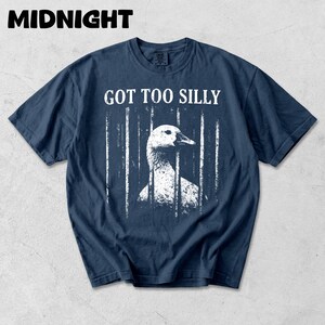 Op de afbeelding: Donkerblauwe t-shirt met een versleten afbeelding van een gans achter tralies. De tekst "GOT TOO SILLY" staat boven de gans. Het woord "MIDNIGHT" staat bovenaan het t-shirt.