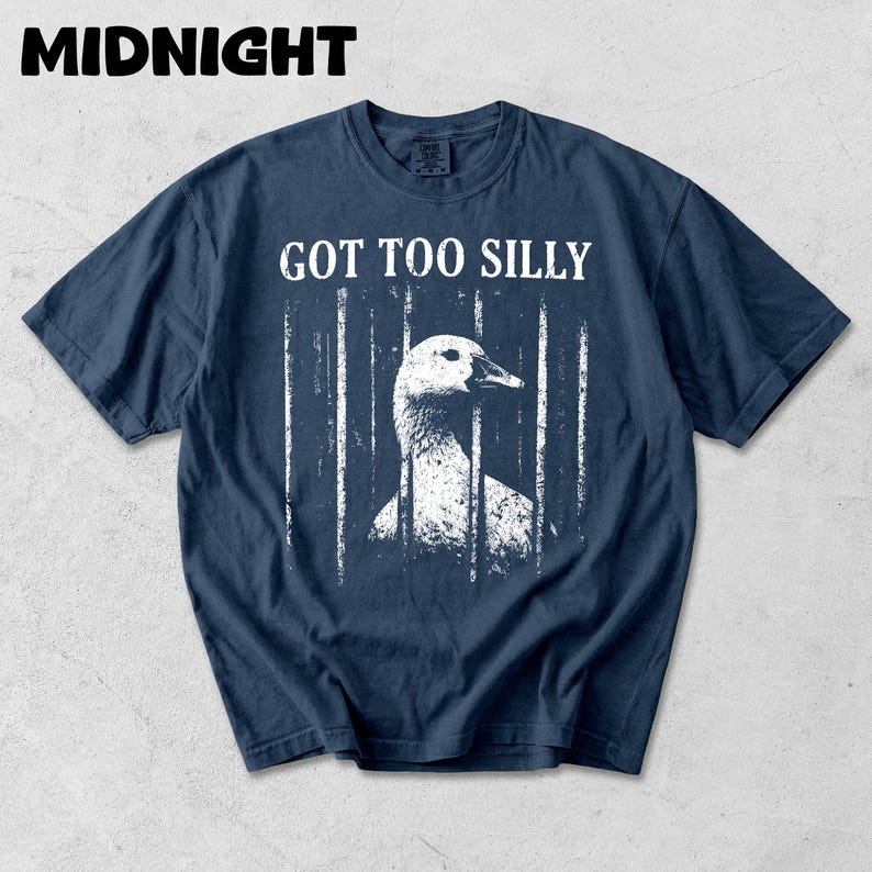 Op de afbeelding: Donkerblauwe t-shirt met een versleten afbeelding van een gans achter tralies. De tekst "GOT TOO SILLY" staat boven de gans. Het woord "MIDNIGHT" staat bovenaan het t-shirt.