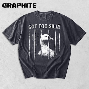 Op de afbeelding: Grafietkleurig t-shirt met de tekst "GOT TOO SILLY" boven een witte illustratie van een gans achter tralies. Het shirt heeft een vintage, versleten uitstraling.