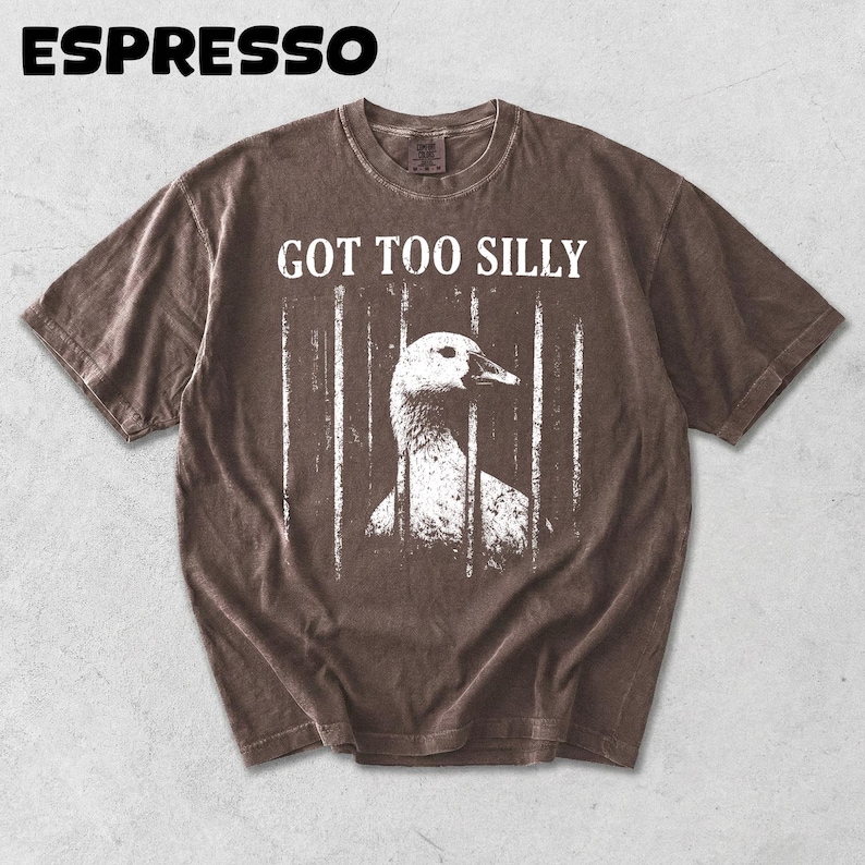 Op de afbeelding: Espresso-kleurig t-shirt met de tekst "GOT TOO SILLY" boven een witte afbeelding van een gans achter tralies. Het woord "ESPRESSO" staat bovenaan gedrukt. Het shirt heeft een vintage, versleten uitstraling.