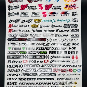 May include: A sheet of stickers featuring various automotive and racing-related logos and text. The stickers are in various colors, including red, black, white, and yellow. The sheet includes logos such as "Animal Style", "Endless", and "Project μ".