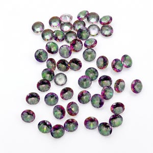 May include: A collection of round, faceted gemstones featuring an iridescent finish. Each stone displays a spectrum of colors including green, purple, and silver tones, reflecting light with a brilliant, multi-colored sheen across their surfaces.
