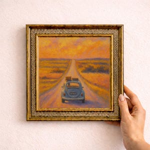 Könnte beinhalten: Ölgemälde in einem goldenen Rahmen, das ein blaues Oldtimer-Auto auf einer langen Straße bei Sonnenuntergang zeigt. Das Gemälde hat eine warme Farbpalette aus Orange, Gelb und Blau. Das Auto hat Gepäck auf dem Dach.