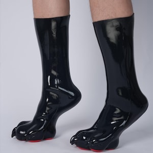 May include: Black, glossy, knee-high boots with a unique paw design. The boots have a smooth, reflective surface and feature three-toed feet with red soles. The boots are a distinctive fashion statement.