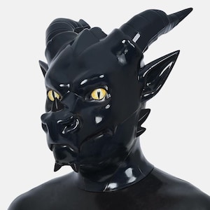 Peut inclure: Un masque en latex noir brillant avec des yeux jaunes, des cornes et des oreilles pointues. Le masque présente un design détaillé, comprenant un museau, des crocs et un front texturé, créant une apparence de créature démoniaque ou fantastique. Le masque couvre la tête et le cou.