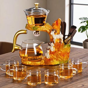 Puede incluir: Un juego de té que incluye una tetera de cristal con asa dorada, un infusor de cristal y seis tazas de cristal llenas de líquido ámbar. El conjunto cuenta con una base decorativa con forma de paisaje rocoso, tres figuras de cabras y utensilios.