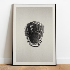 May include: Framed print featuring a black baseball glove with white stitching. The glove is set against a light grey backdrop, highlighting its detailed construction. This monochromatic image is a stylish representation of a classic sporting item.