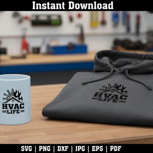 May include: A light blue mug and a gray hoodie with the text "HVAC LIFE" in black. The mug and hoodie are on a wooden surface. The background is a workshop with tools.