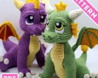 May include: Two crocheted dragon toys, one purple and one green, with yellow accents on their horns, wings, and bellies. The dragons have large, expressive eyes and are sitting upright. The image includes the text "PATTERN" and "PDF File".