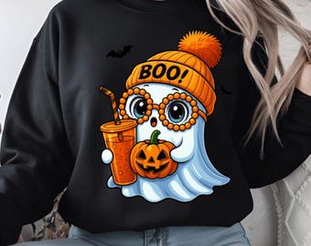 May include: Black sweatshirt with a cartoon ghost wearing an orange beanie with the word "BOO!" and glasses. The ghost holds a pumpkin and a drink. Two black bats are flying in the background. A fun Halloween design.