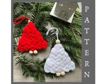 May include: Two handmade Christmas tree decorations, one red and one white, with wooden bead accents. The decorations are displayed on a bed of evergreen branches. The word "PATTERN" is printed vertically on the right side of the image.