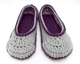 May include: A pair of handmade crochet slippers. The slippers are grey with a purple interior and trim. The crochet stitch is visible, and the slippers appear soft and comfortable. The design is simple and classic.