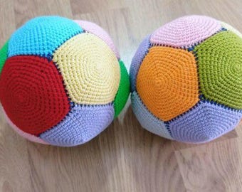 May include: Two colourful, crocheted balls with geometric patterns. Each ball features a patchwork design of various colours, including red, blue, yellow, green, orange, and pink. The balls are made of soft yarn and are likely intended for play or decoration.