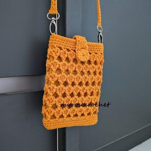 May include: A mustard yellow crochet crossbody bag with a decorative openwork pattern. The bag has a flap closure with a button and a long strap with silver-tone hardware. The text "myrosecrochet" is visible on the bag.