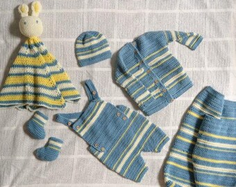 May include: A set of hand-knitted baby clothes in blue, yellow, and white stripes. The set includes a hat, cardigan, dungarees, booties, and a bunny comforter. The items are displayed on a white, textured surface.