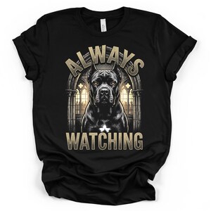 Könnte beinhalten: Ein schwarzes Kurzarm-T-Shirt mit einer Grafik eines Cane Corso Hundes vor einem gotischen Torbogen. Der Text ALWAYS steht über dem Hund und WATCHING darunter, geschrieben in einer metallisch goldenen Serifenschrift.
