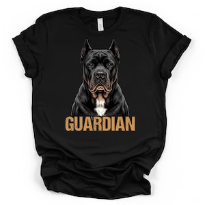Könnte beinhalten: Ein schwarzes T-Shirt mit kurzen Ärmeln und einer zentralen Grafik eines schwarzen Hundes mit einem weißen Fleck auf der Brust. Unter dem Hund ist das Wort GUARDIAN in einer abgenutzten, beigefarbenen Blockschrift aufgedruckt.