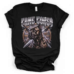 May include: A black t-shirt featuring a graphic print of a Cane Corso dog head in profile. Behind the dog is a circular shield with crossed swords and lightning bolts. The text CANE CORSO is printed in a metallic silver font above the dog.