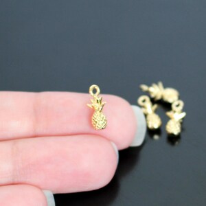May include: Gold pineapple charms, perfect for jewelry making or crafting projects. These small charms are a fun and tropical addition to any design.