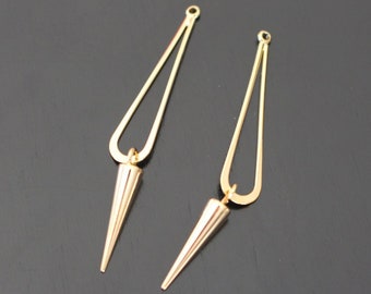 Könnte beinhalten: Ein Paar goldfarbene Ohrringe mit geometrischem Design. Jeder Ohrring hat einen langen, dünnen, tropfenförmigen Anhänger mit einer spitzen Spitze.