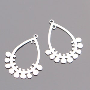 May include: Two silver teardrop-shaped earring blanks with a decorative border of small circles around the edge. The blanks have a loop at the top for attaching earring wires.