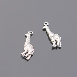 May include: Two silver giraffe charms with a textured surface. The charms are perfect for adding a touch of whimsy to jewelry projects.