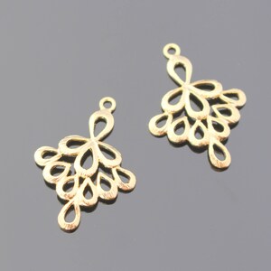 May include: Two gold-colored metal earring charms with a delicate, intricate design resembling a cluster of small, teardrop-shaped flowers.