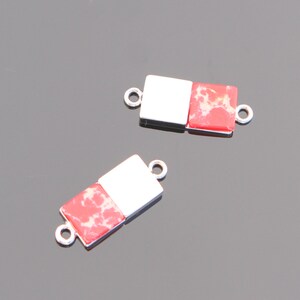 May include: Two silver-toned metal connector pieces with red and white marbled stone inserts. Each piece has two loops for attaching to jewelry.