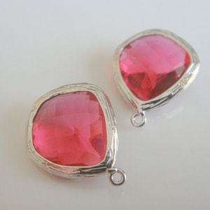 May include: Two pink crystal pendants with silver settings. Each pendant has a loop for attaching to a necklace or bracelet.