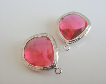 Puede incluir: Dos colgantes de cristal rosa con engastes plateados. Cada colgante tiene un bucle para sujetarlo a un collar o pulsera.