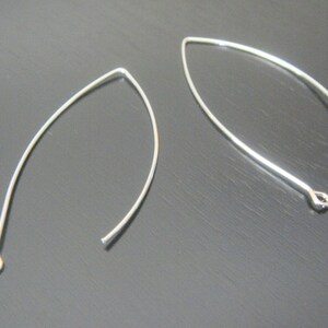 May include: Two silver earring hooks with a loop at one end and a small loop at the other end.
