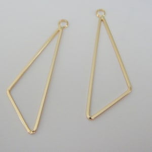 May include: Two gold triangle shaped earring findings with a loop at the top.