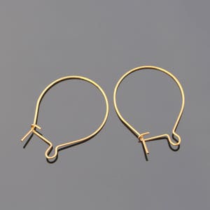 Op de afbeelding: Twee gouden creolen met een eenvoudig draadontwerp.