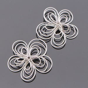 May include: A pair of silver wire earrings shaped like flowers. Each earring is made of multiple overlapping circles.