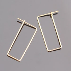 May include: A pair of gold-toned rectangle shaped hoop earrings.