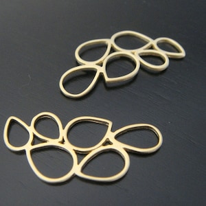May include: Two gold metal leaf-shaped embellishments. Each embellishment is made of multiple connected ovals.