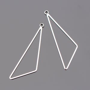 Peut inclure: Deux apprêts de boucles d'oreilles en forme de triangle argentés avec des anneaux de saut.