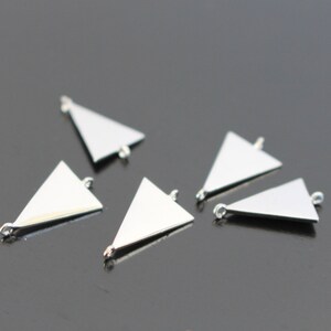 May include: Six silver triangle pendant charms with jump rings. The charms are flat and have a shiny finish.