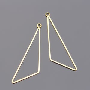 May include: Two gold triangle shaped earring blanks with jump rings at the top.